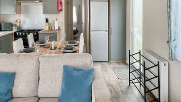A compact living space with a kitchenette, dining area, and a sofa with cushions.