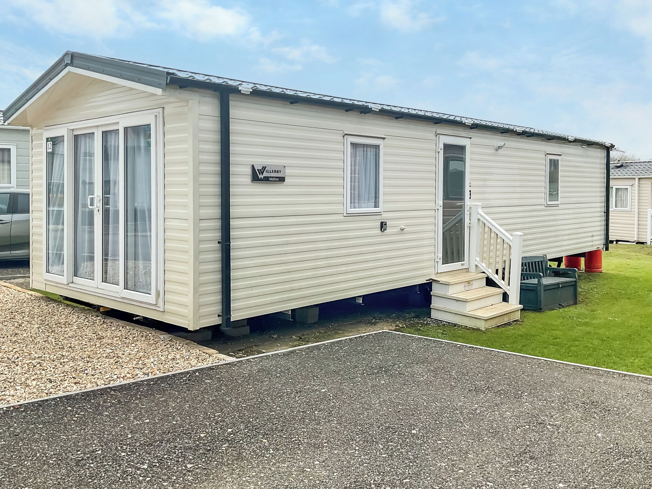 A mobile home with a nameplate, a front door, a set of stairs, and a small porch area.