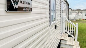 Uma casa móvel com uma placa que diz 'WILLERBY Malton' e uma escadaria de madeira que dá para um deck.