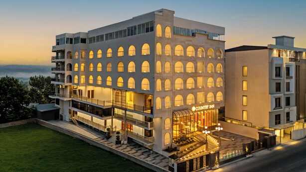 Un hotel modern amb diverses plantes, una entrada destacada i una façana ben il·luminada.