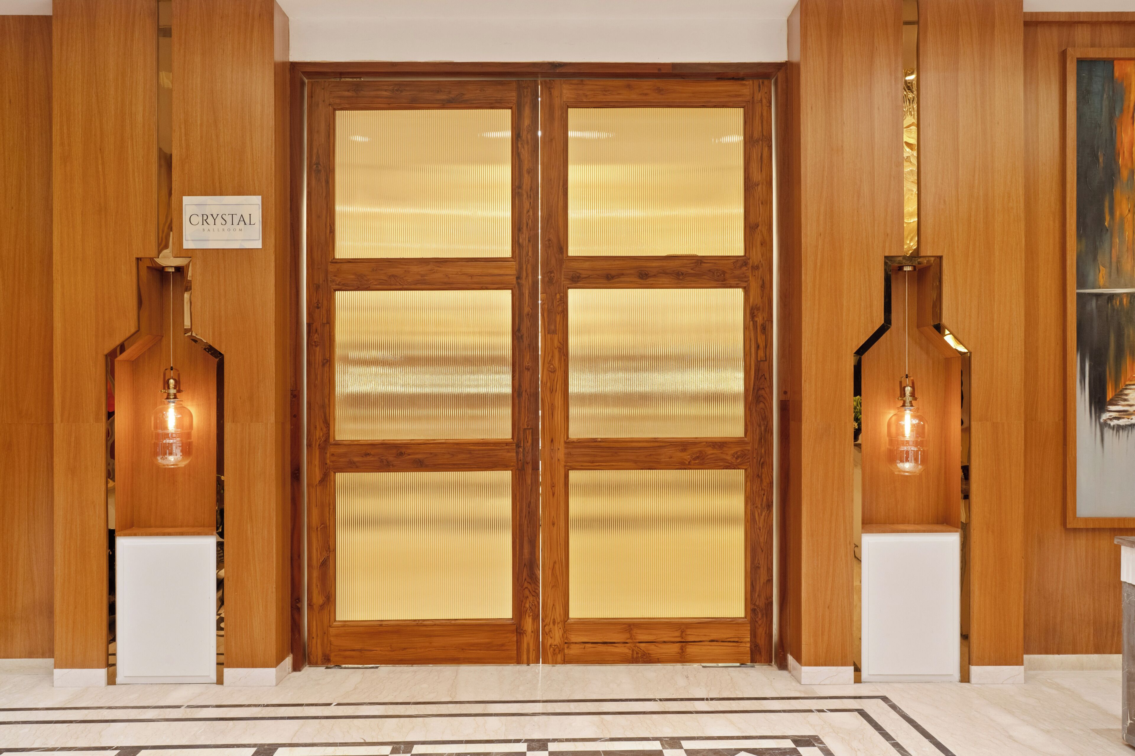 A wooden double door with frosted glass panels, a sign above the door, and two pendant lights on either side.
