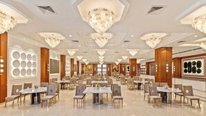 Una espaiosa sala de banquets amb diverses taules rodones, elegants llums penjants i un sòl de marbre polit.