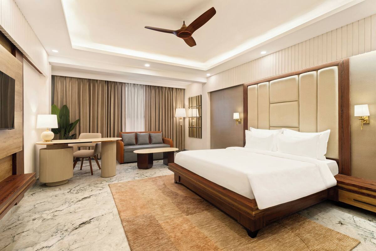 Una habitación de hotel con una cama grande, un escritorio, un sofá y un ventilador de techo.