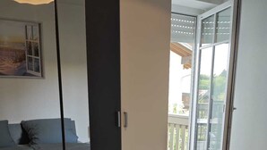 A bedroom with a bed, a wardrobe, and a sliding glass door leading to a balcony. - Apartment with mountain view, 60sqm & balcony (Waging am See)