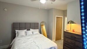 A bedroom with a bed, a ceiling fan, a dresser, and a mirror.