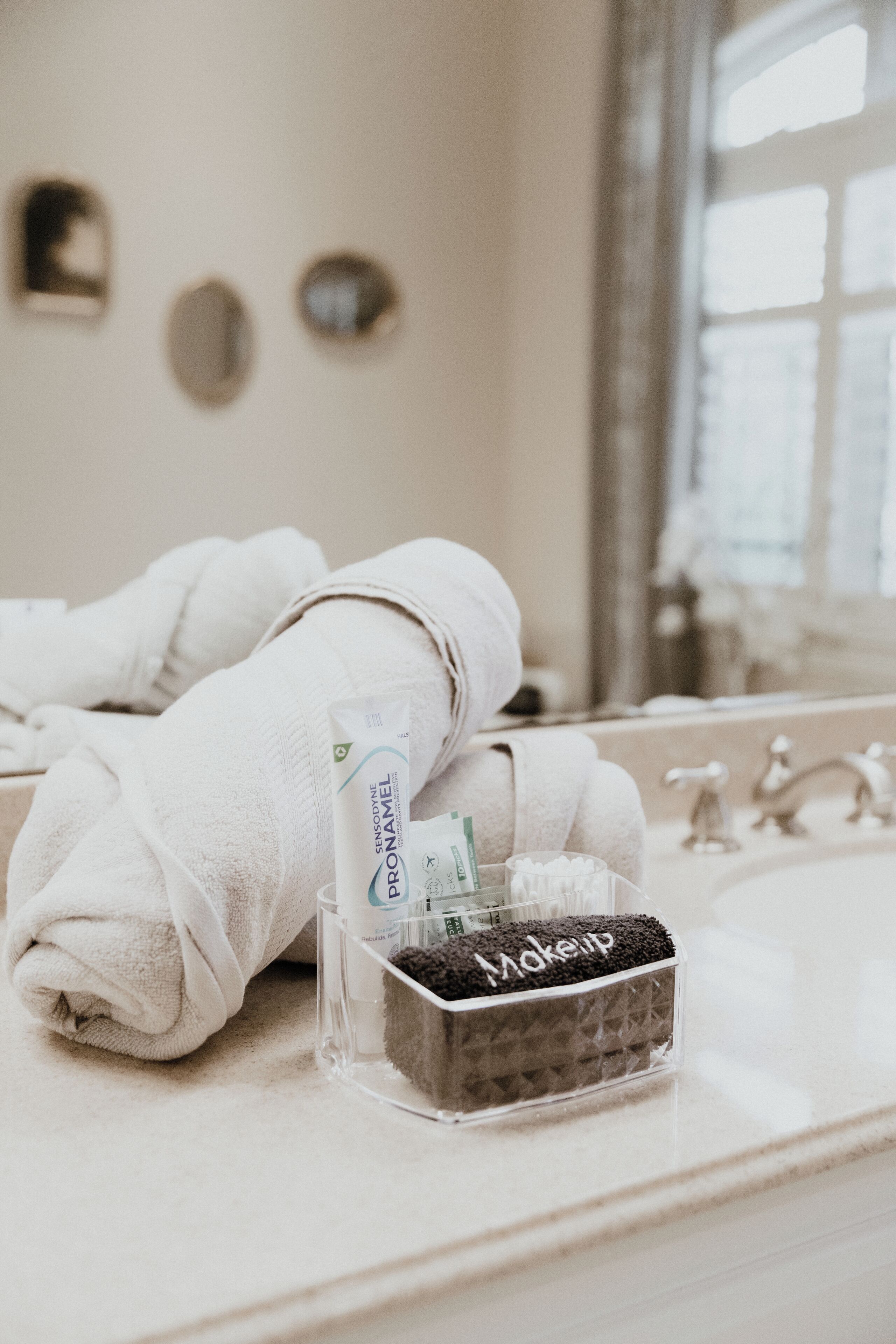 A bathroom with a towel, a makeup brush, and a bottle of lotion on the counter.