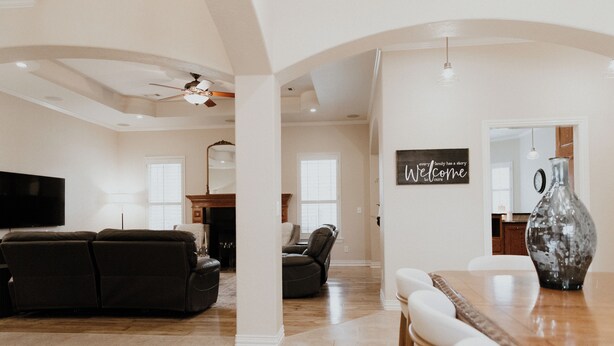 A spacious living area with a large flat-screen TV, a dark-colored sofa, a dining table with chairs, and a decorative vase. - Sleek Ardmore Home, near lake Murray, Mercy Hospital, Lakecrest, Winstar casinos (Ardmore)