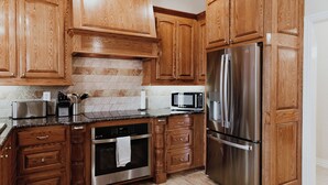 A kitchen with wooden cabinets, stainless steel appliances, a microwave, and a tiled backsplash. - Sleek Ardmore Home, near lake Murray, Mercy Hospital, Lakecrest, Winstar casinos (Ardmore)
