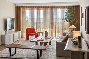 A modern living room with a flat-screen TV, a red chair, a wooden coffee table, a sofa, and a large window with curtains. - Apartment R111 - Designer Style and Elegance (Scarborough)