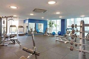 A gym with various exercise equipment, large windows, and a blue accent wall. - Apartment R111 - Designer Style and Elegance (Scarborough)