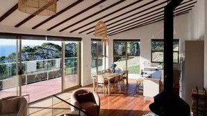 A modern interior with a dining area, large windows, and a fireplace. - The Hemp House | Table Cape Ocean Views (Table Cape)