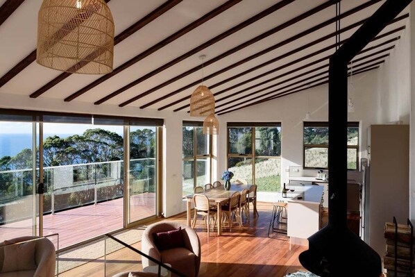 A modern interior with a dining area, large windows, and a fireplace.