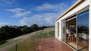 A modern house with a wooden deck, large sliding glass doors, and a view of the surrounding landscape. - The Hemp House | Table Cape Ocean Views (Table Cape)