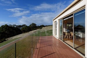 A modern house with a wooden deck, large sliding glass doors, and a view of the surrounding landscape. - The Hemp House | Table Cape Ocean Views (Table Cape)