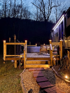 Een houten terras met een bankje en een bordje waarop staat 'Jenny Lee's Creekside Bliss'.