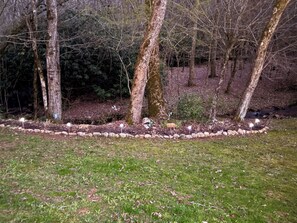 Een aangelegde tuin met bomen, een stenen rand en een gazon.