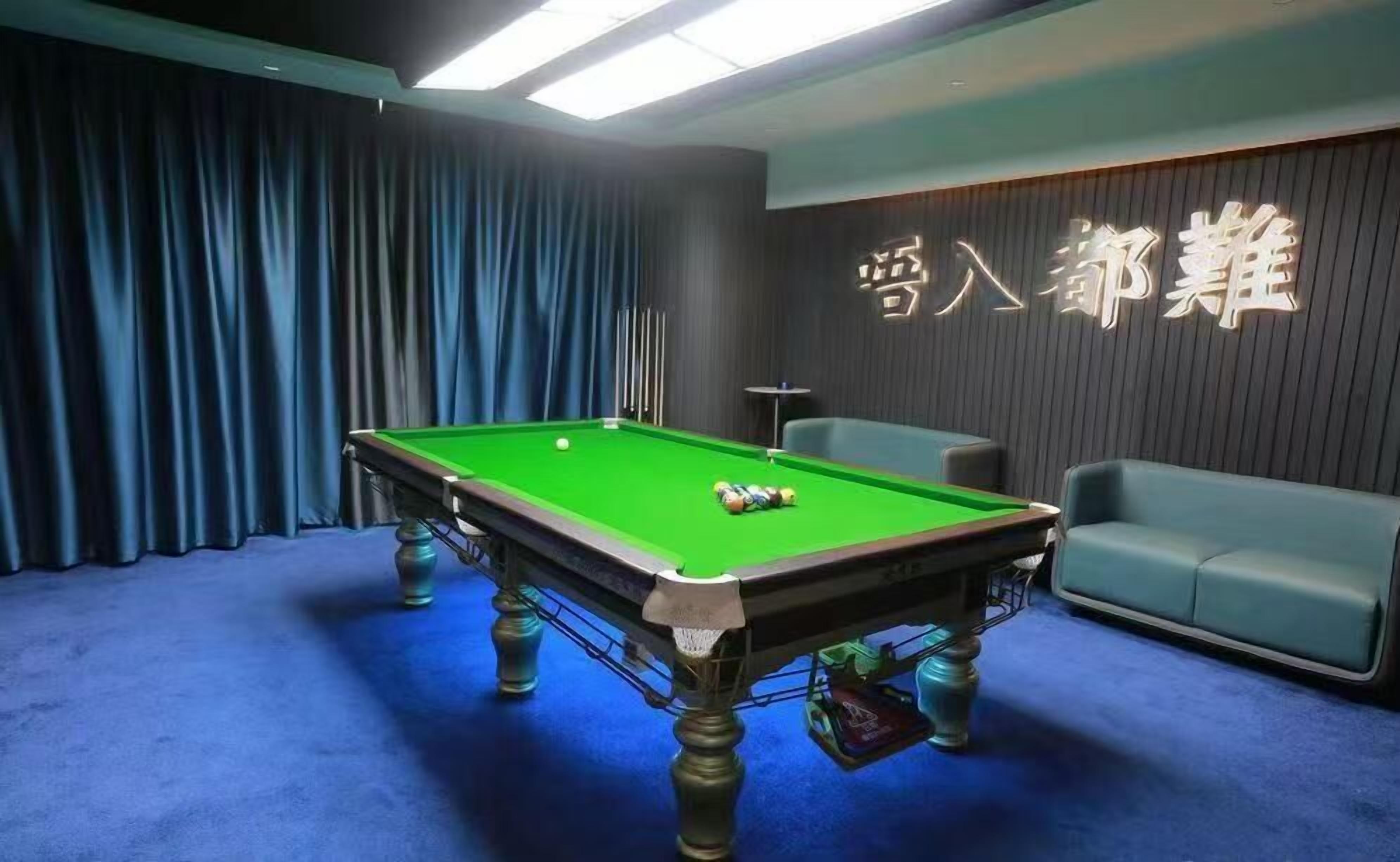 A pool table with balls, a sofa, and a wall with illuminated text.