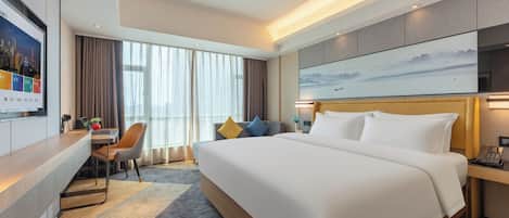 A hotel room with a large bed, a desk with a laptop, a chair, and a TV.