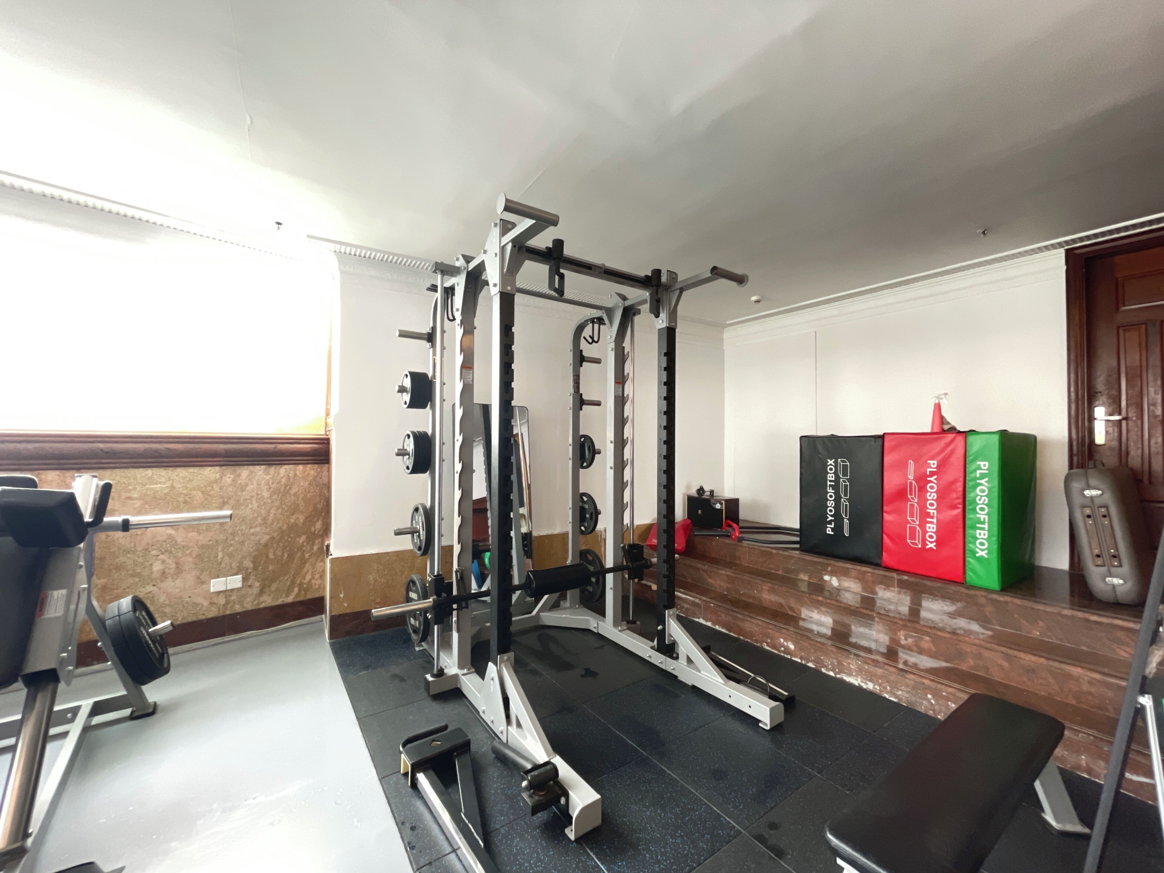 Un gimnasio con equipo de levantamiento de pesas, una banca y cajas PlyoSoftBox.