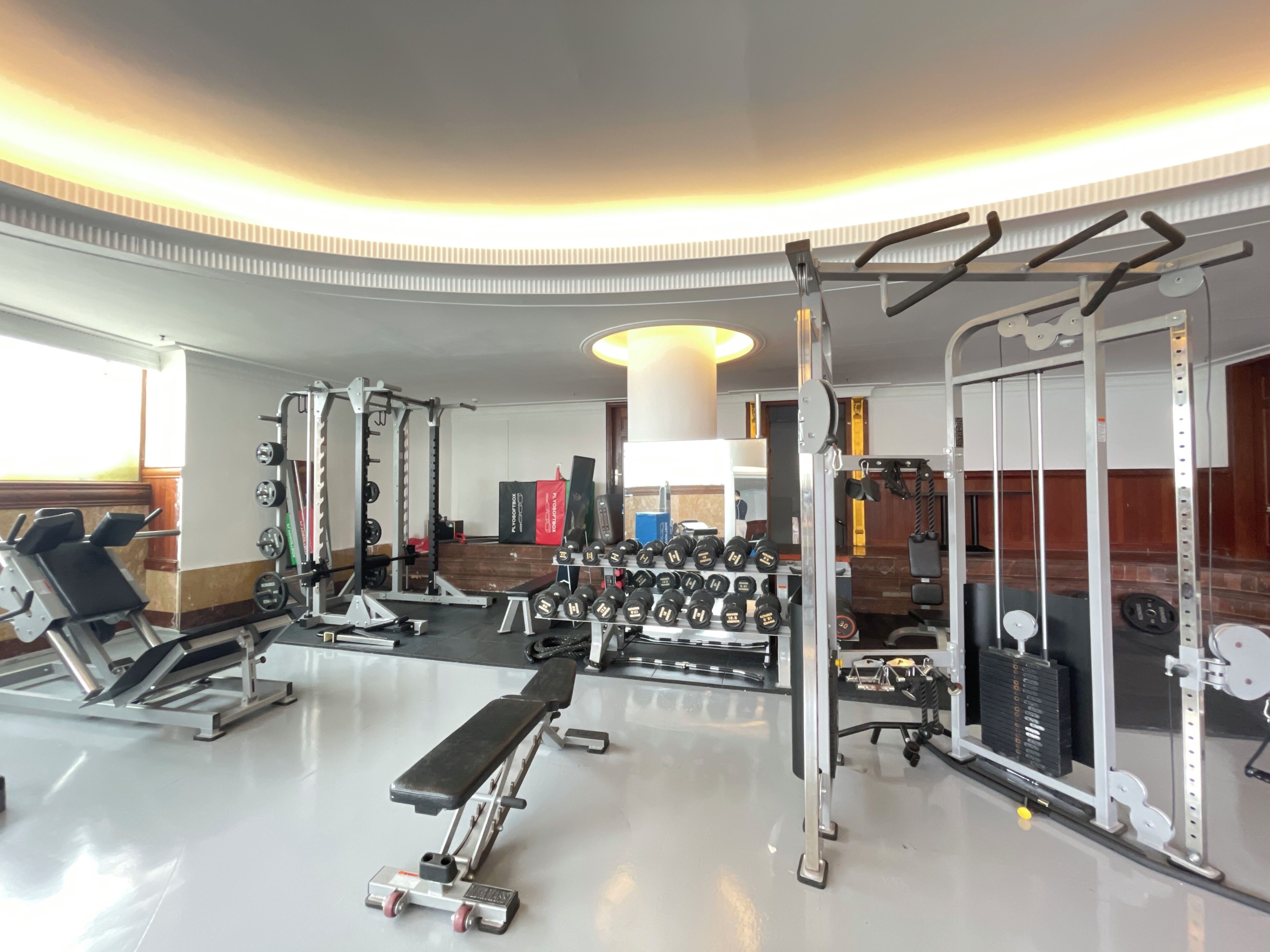 A gym with weightlifting equipment, dumbbells, and cardio machines.