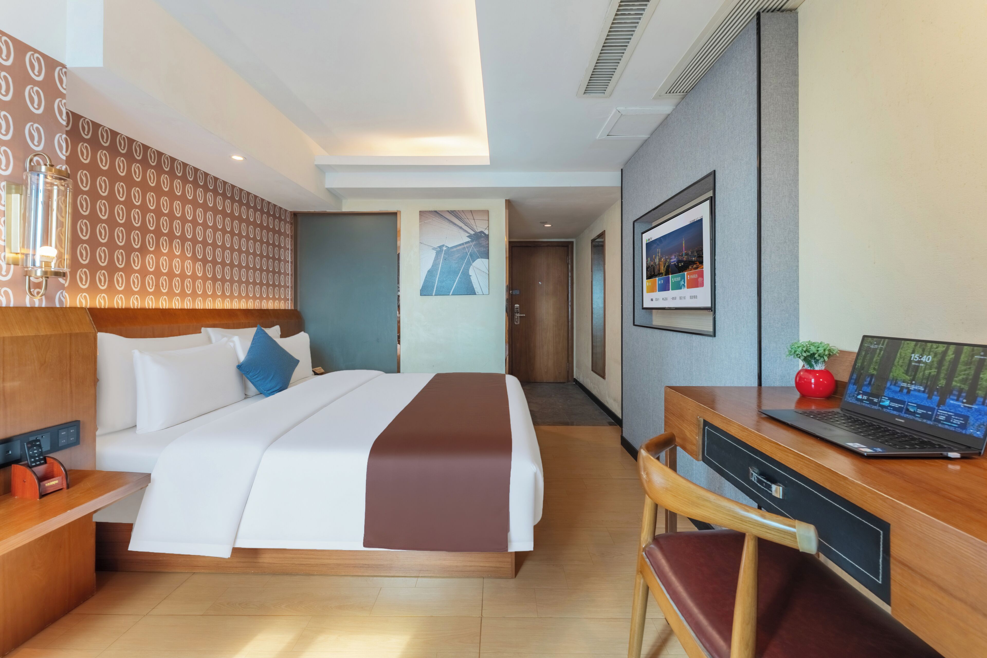 Habitación de hotel con cama, escritorio, silla y una computadora portátil.