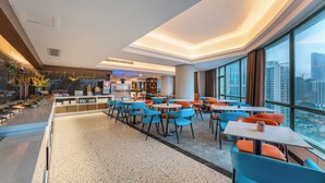 Un moderno vestíbulo de hotel con zona de comedor, ventanas amplias y vistas a la ciudad.