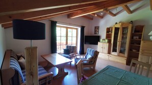 A cozy room with a wooden ceiling, a sofa, a table, a TV, and a cabinet. - Kilian Reiter vacation apartment (Ruhpolding)