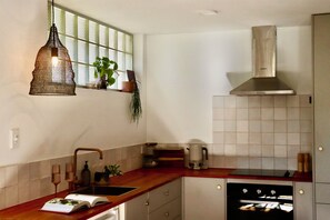 Een keuken met een houten aanrecht, een spoelbak, een fornuis en een hangende lamp.