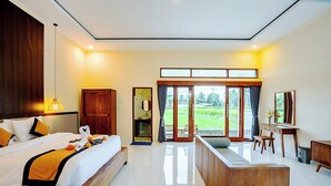 A hotel room with a large bed, a desk, a chair, and a view of the outdoors. - Puri Prana Villa (Ubud)