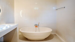 A bathroom with a freestanding bathtub, a towel rack, and a sink. - Puri Prana Villa (Ubud)