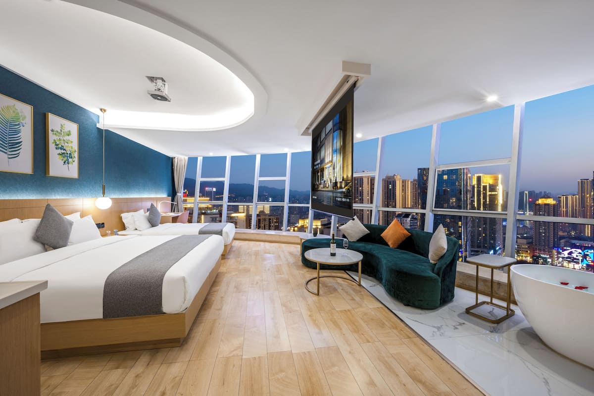 Une chambre d’hôtel moderne avec un grand lit, un canapé, une petite table, une baignoire et une vue sur la ville.