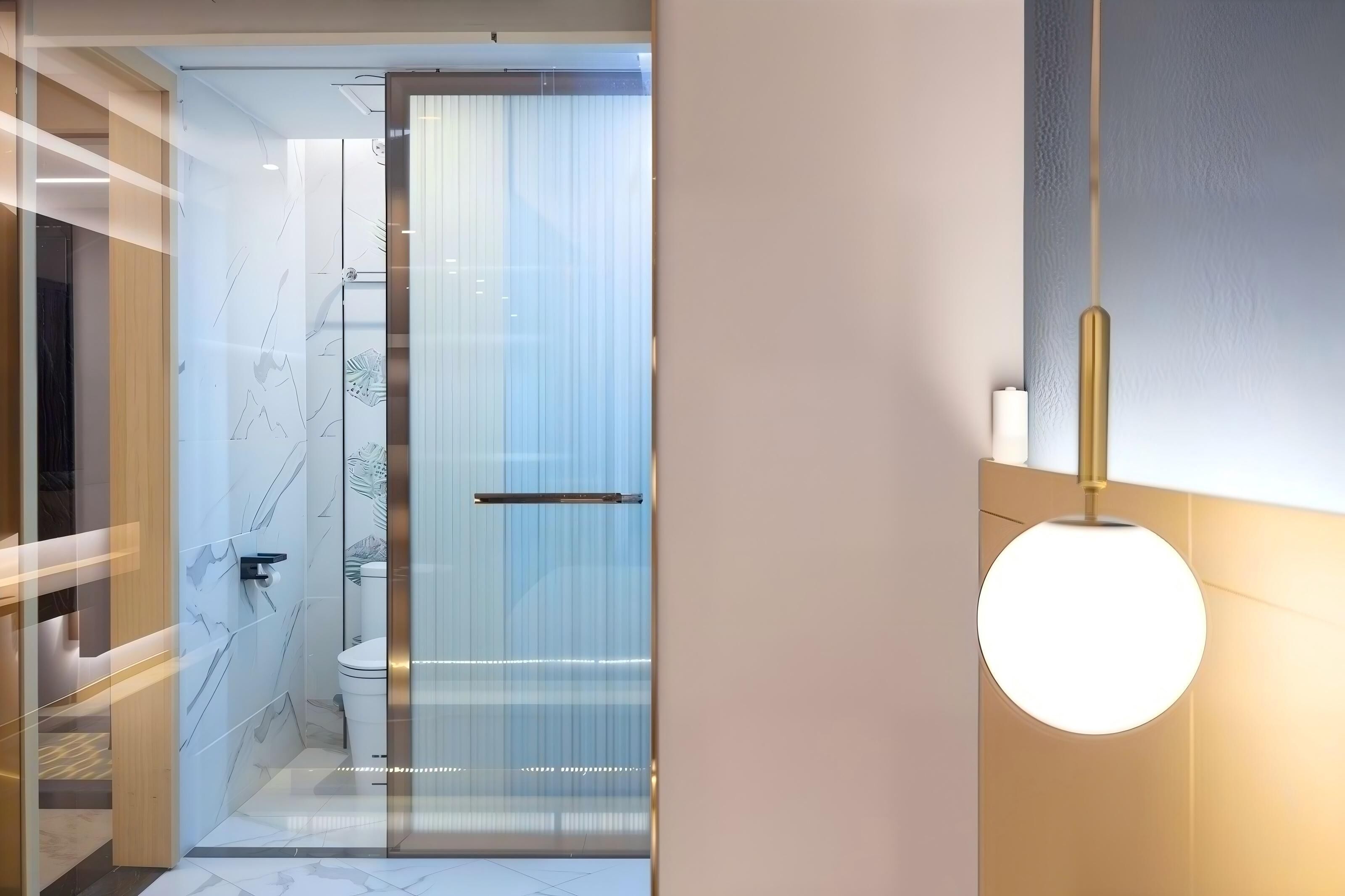 A modern bathroom with a glass shower enclosure, a toilet, and a round pendant light.