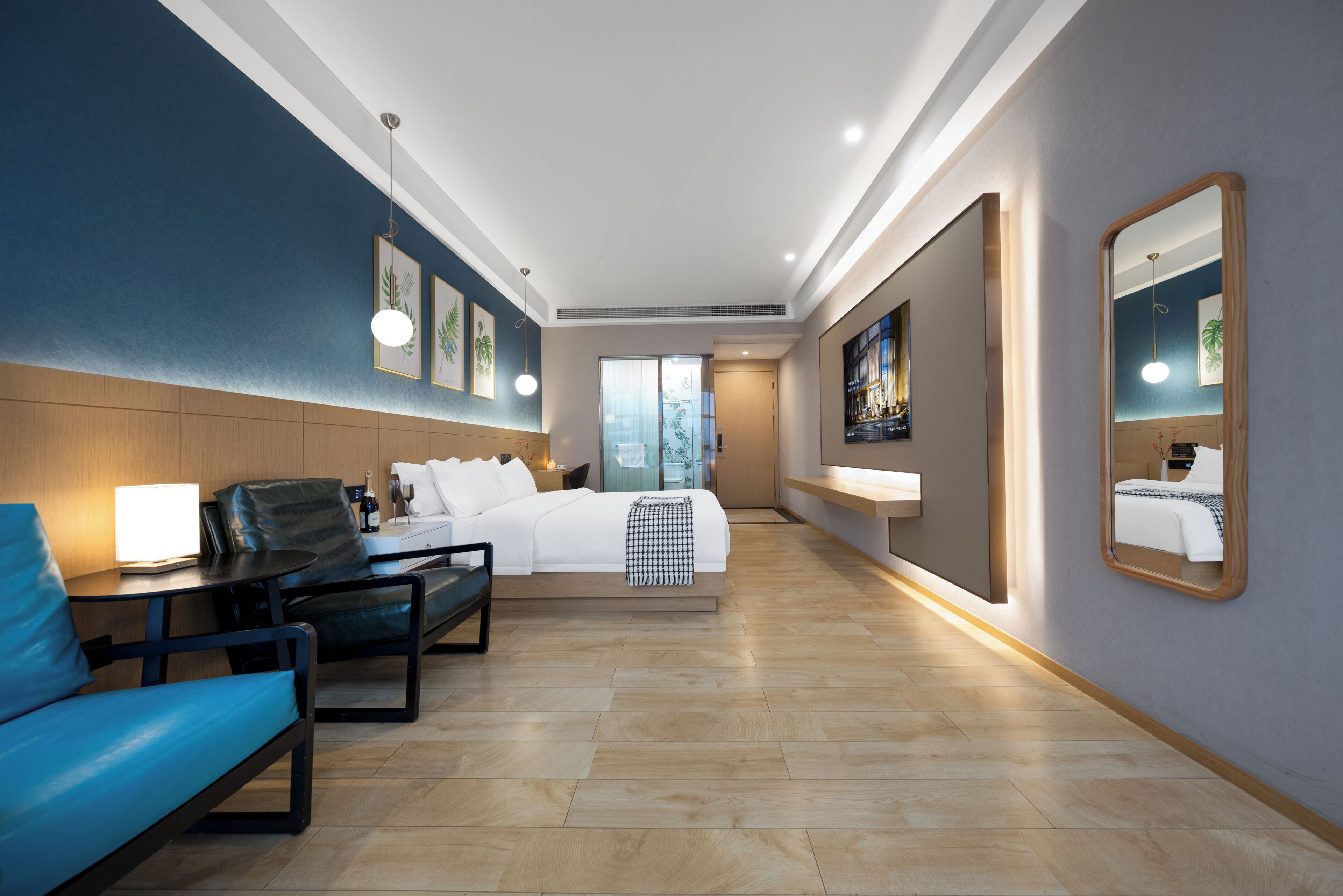A hotel room with a bed, seating area, bedside table, lamp, and artwork.