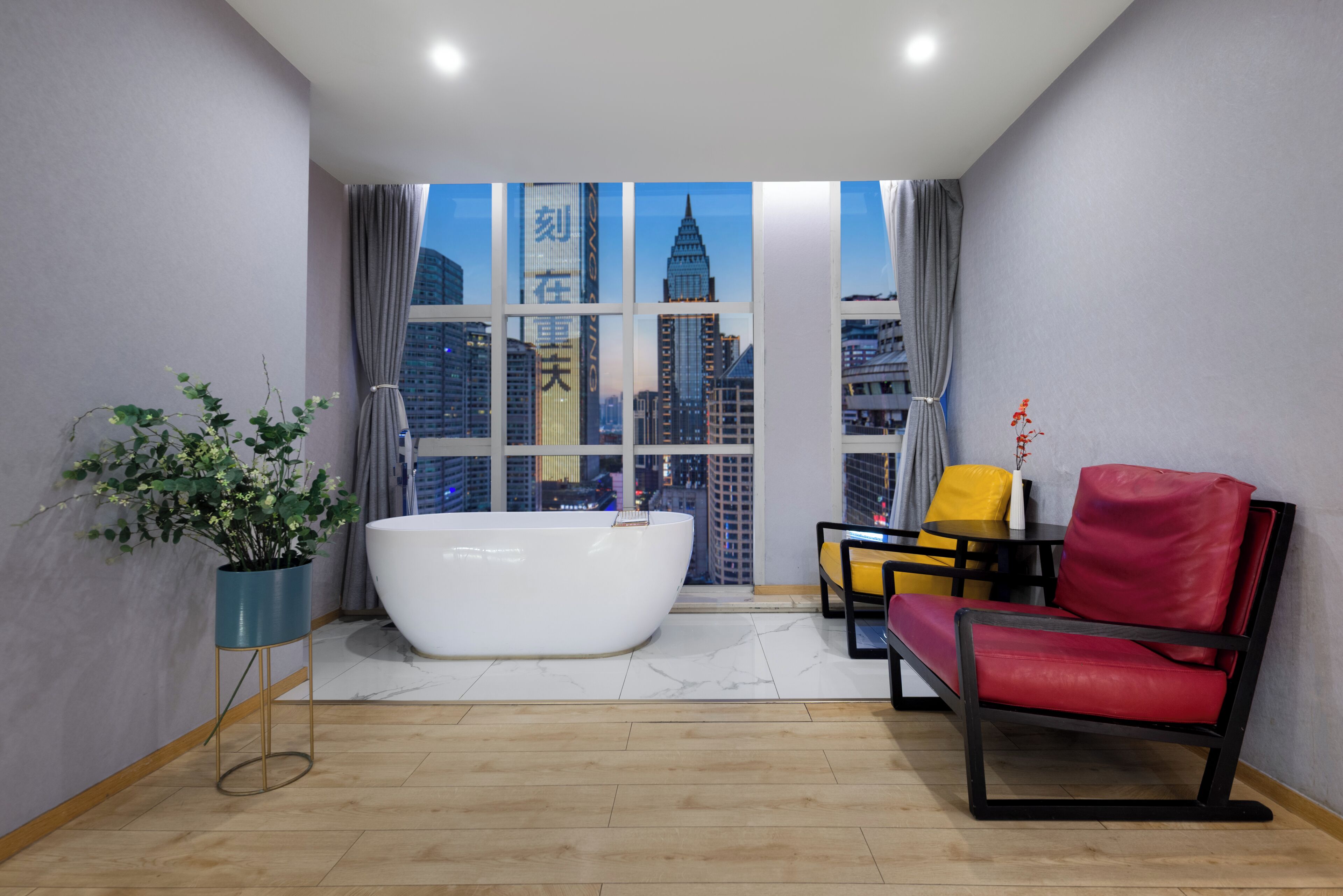 A modern bathroom with a bathtub, a red chair, a yellow chair, and a potted plant.