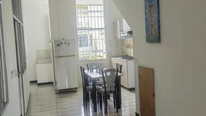 Une cuisine avec une table et des chaises, un ventilateur de plafond et une fenêtre avec des barreaux.