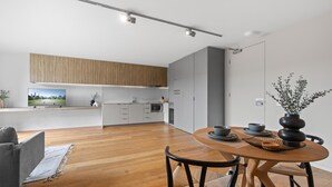Eine moderne Küche mit weißen Schränken, einer Holz Arbeitsplatte und einem Essbereich mit rundem Tisch und Stühlen.