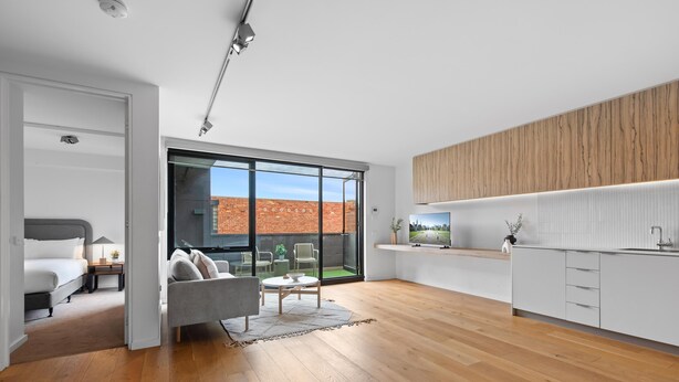Eine moderne Küche mit weißen Schränken, einer Holz Arbeitsplatte und Blick auf ein Backsteingebäude.