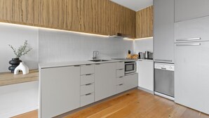 Eine moderne Küche mit Holzvertäfelung, weißen Schränken und Edelstahlgeräten.