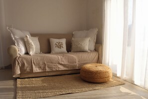 A beige sofa with patterned cushions, a woven ottoman, and a woven rug in a room with sheer curtains. - Relaxation in private garden, outdoor kitchen, private parking lot (Diano Castello)