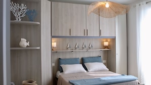 Ein Schlafzimmer mit einem Bett, einer Hängelampe und Dekorationen auf Regalen.