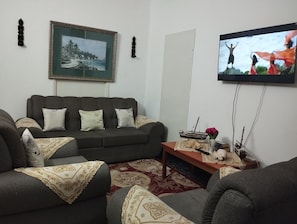 Een woonkamer met een bank, een salontafel, een lijst met een afbeelding en een televisie.