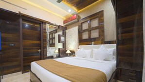Ein Hotelzimmer mit einem großen Bett, Holzvertäfelung, einem Spiegel und einem Nachttisch mit einer Lampe.