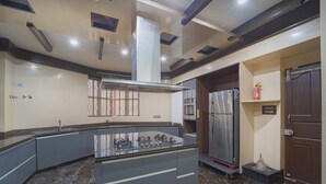 A modern kitchen with a central island, built-in oven, and stainless steel refrigerator. - Alaya Stays Royal Valora 5BHK villa (Bengaluru)
