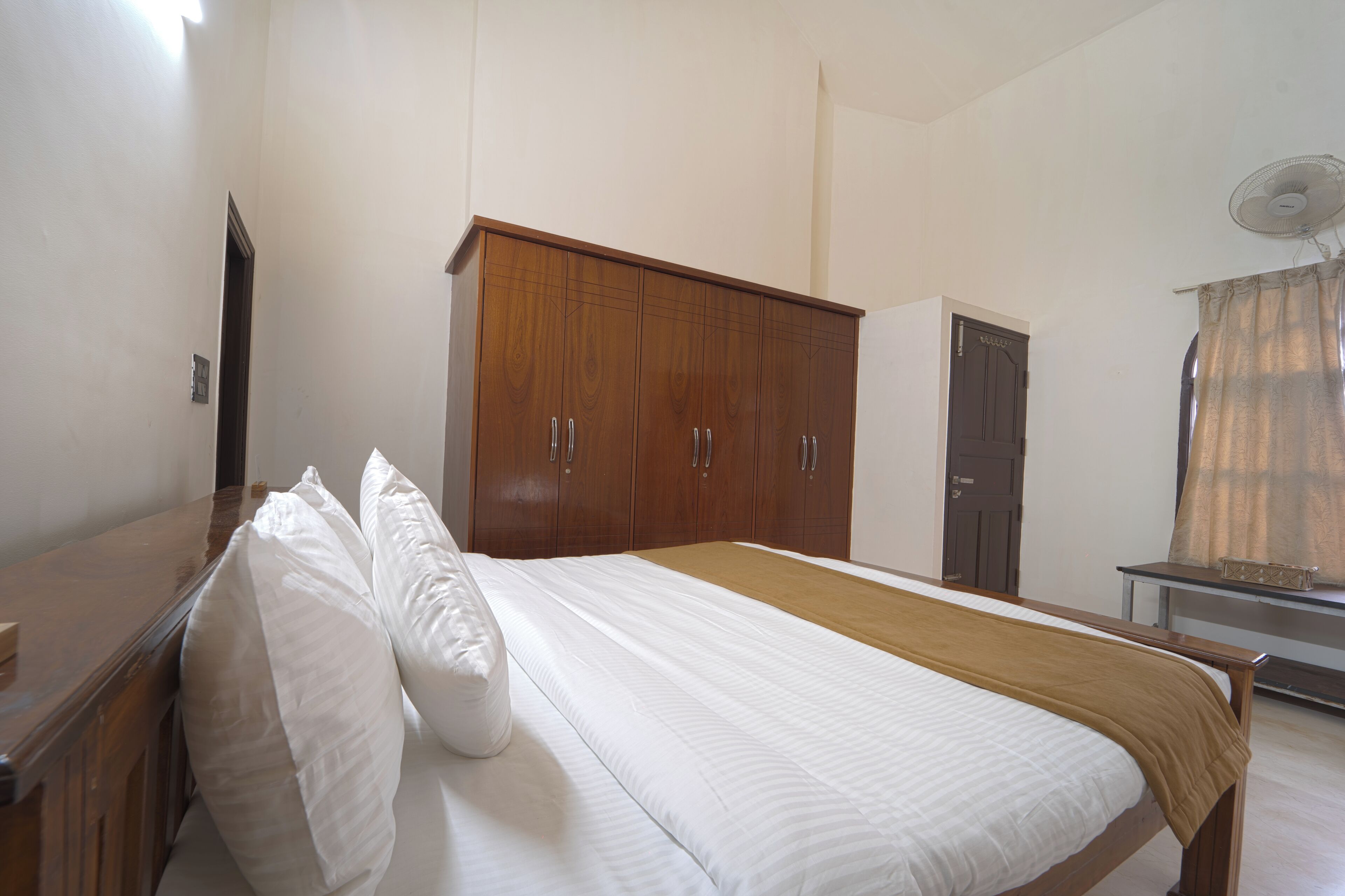 Un dormitorio con cama, armario de madera y escritorio.