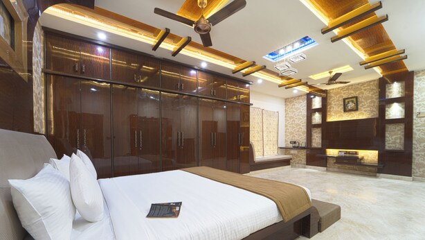 A modern bedroom with a large bed, built-in wardrobe, ceiling fans, and recessed lighting. - Alaya Stays Royal Valora 5BHK villa (Bengaluru)