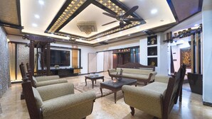 A spacious living room with a high ceiling, a ceiling fan, a chandelier, and a sofa. - Alaya Stays Royal Valora 5BHK villa (Bengaluru)