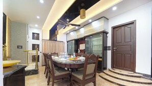 A dining area with a round table, chairs, a ceiling fan, and a door. - Alaya Stays Royal Valora 5BHK villa (Bengaluru)