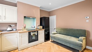 A modern kitchen with white cabinets, a black refrigerator, a green sofa, and a herringbone wooden floor. - 3 bedroom accommodation in Lincoln (Lincoln)
