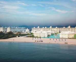 Un hotel a la costa amb diversos edificis, una platja i una zona de piscina.