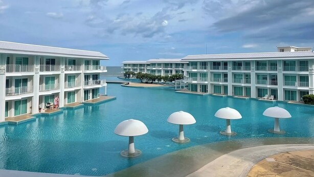Un complexe hôtelier doté d’une grande piscine, de bâtiments à plusieurs étages et offrant une vue sur un ciel dégagé.